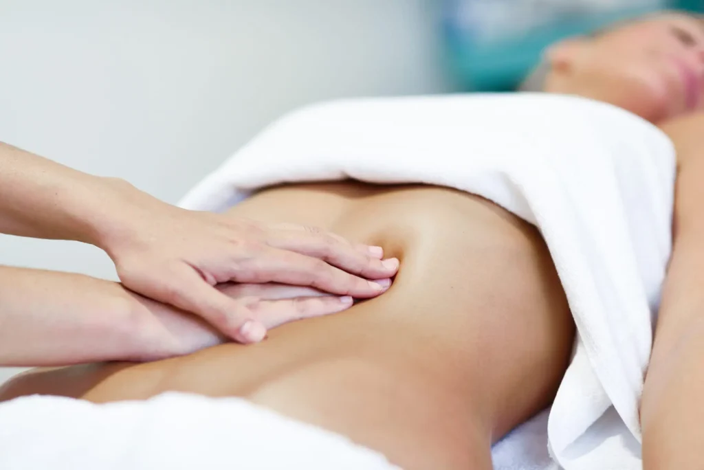 Praticien effectuant une pression ciblée sur le bas-ventre pour un massage